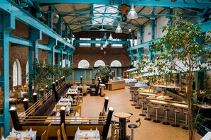 Un restaurante espacioso con techos altos, paredes de ladrillo visto y una zona de bar central.