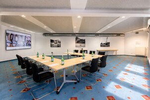 A conference room with a long table, chairs, and a projector screen displaying a presentation.