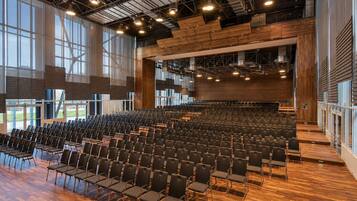 Ein großer Saal mit Reihen von Stühlen, hohen Decken und großen Fenstern.
