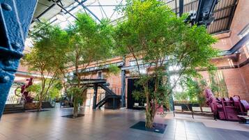 An indoor atrium with a high ceiling, exposed brick walls, and a central staircase.