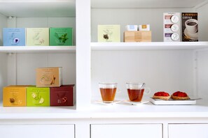 Una estantería con diferentes cajas de té y una bandeja con dos tazas de té y un postre.