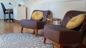 Una sala de estar moderna con dos sillones, una mesita auxiliar y una alfombra estampada.