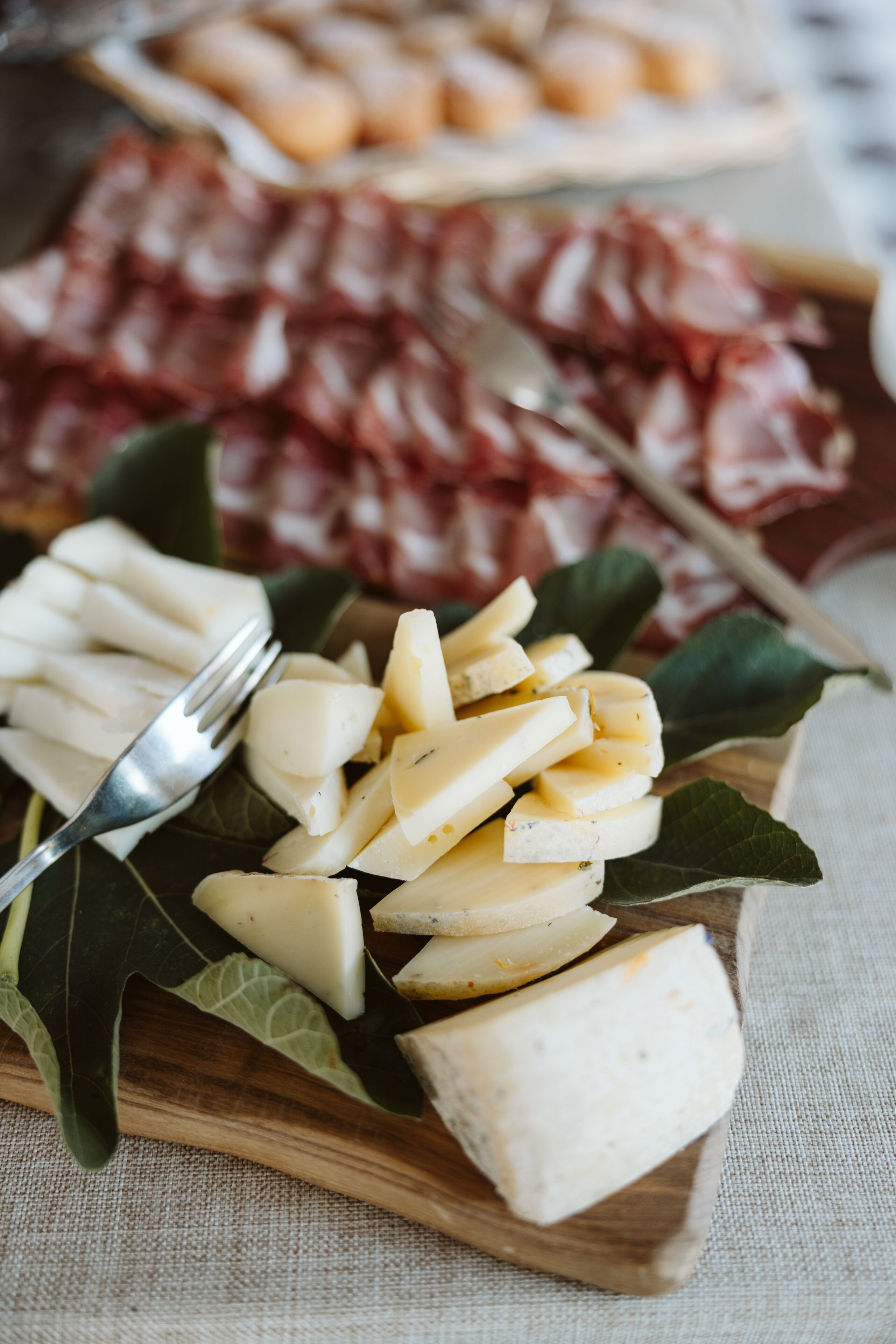 A wooden board with cheese and a fork.