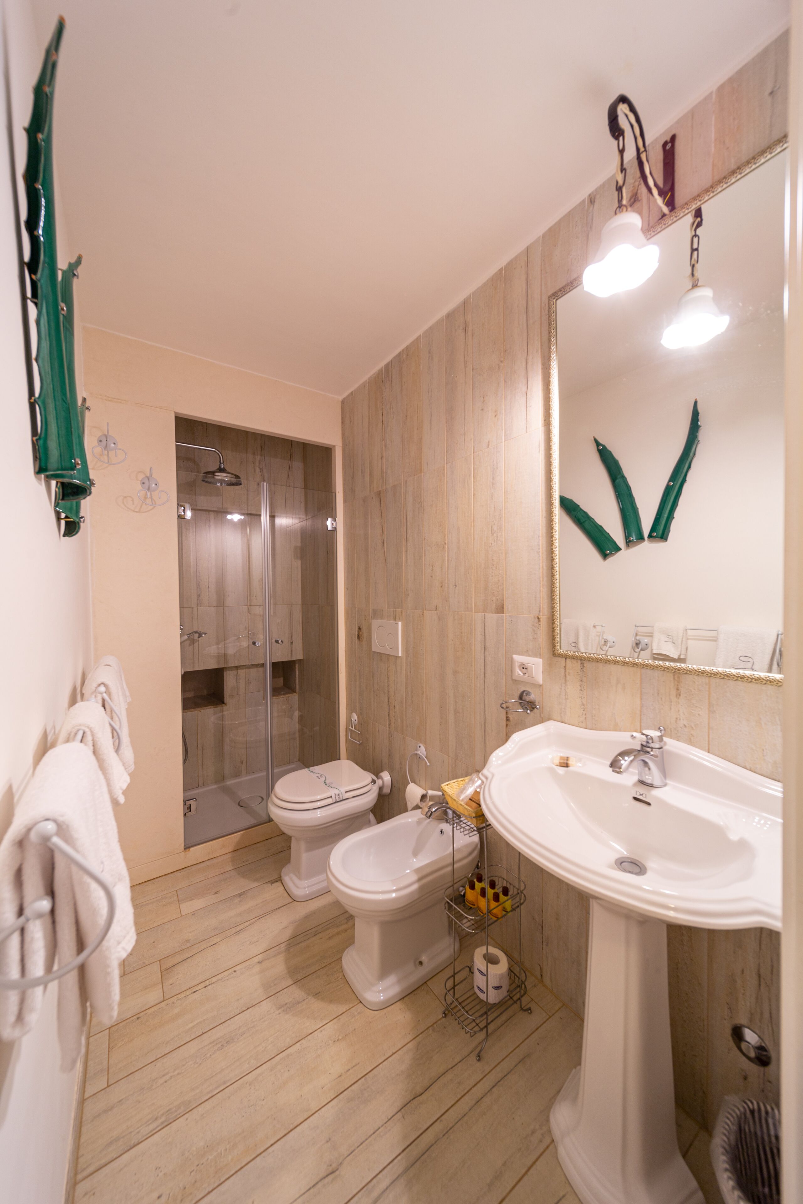 Baño con ducha, dos inodoros, lavamanos y espejo.