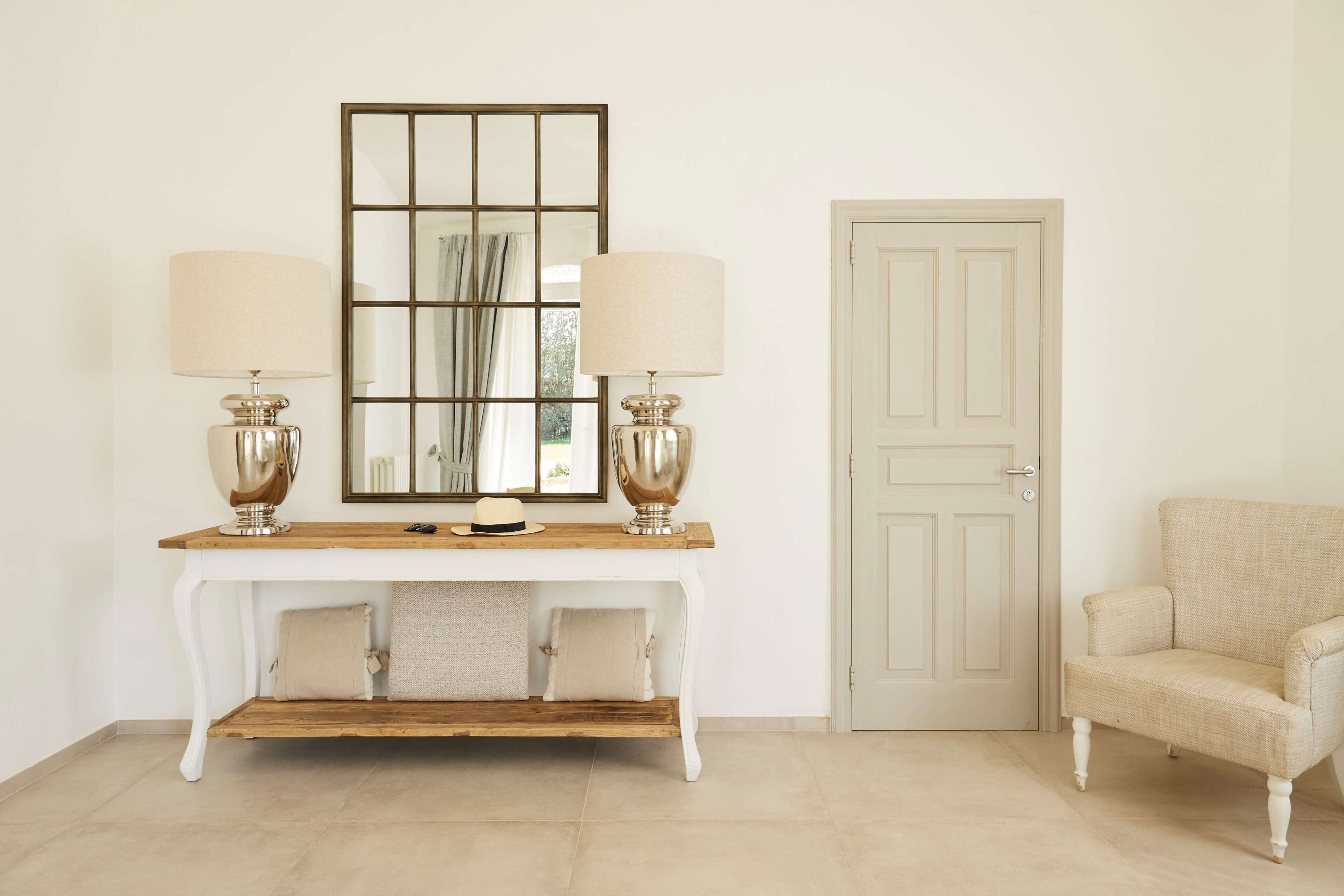 A white console table with two lamps, a mirror, and a door to the right.