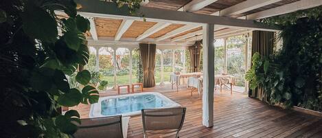 A wooden deck with a hot tub, two chairs, and a table.