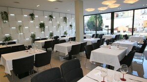 Un restaurant avec de nombreuses tables, des chaises noires et des nappes blanches.