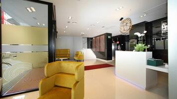 Experience the sleek, modern lobby with a reception desk, stylish armchair, and elegant staircase.