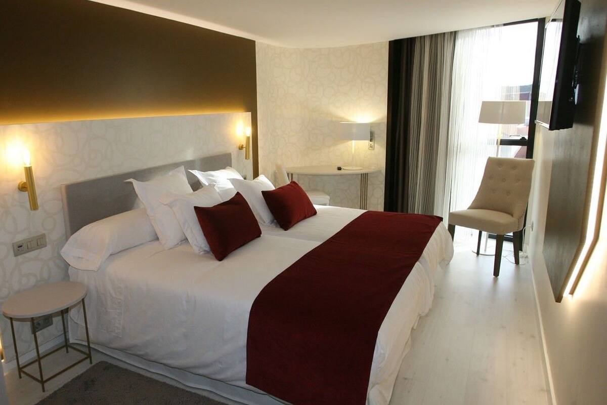 Habitación de hotel con una cama grande, mesitas de noche, un escritorio, una silla y un televisor.