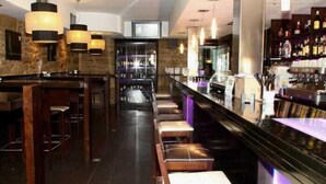 Un espace bar avec des tabourets en bois, un comptoir et un éclairage suspendu.