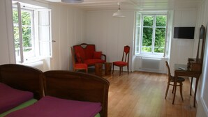 Une pièce comprenant un lit, deux chaises, une table et un téléviseur.
