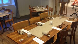 Un espace repas avec des tables et des chaises en bois, des bougies et des serviettes.