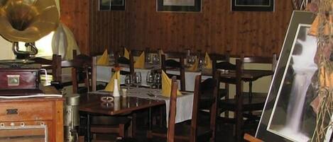 A room with wooden walls, a table set for dining, and a vintage gramophone.