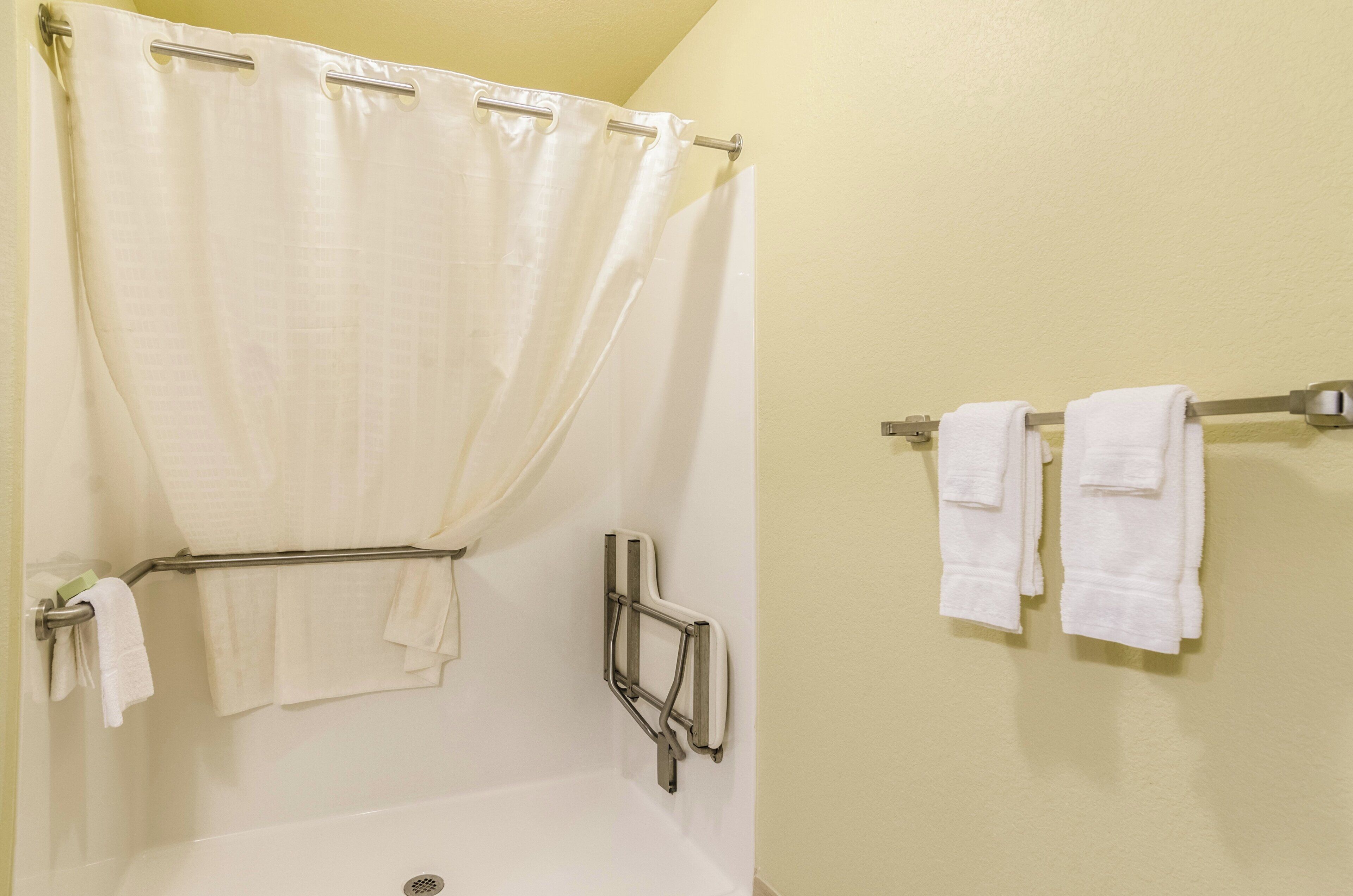 A bathroom with a shower curtain, a bathtub, and towel racks.