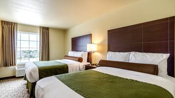 A hotel room with two beds, a large window with curtains, a wall-mounted headboard, and a bedside lamp.