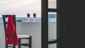 A chair with a red scarf, two glasses of red wine, and a book on a balcony overlooking the sea. - Andros Maisonettes (Andros)