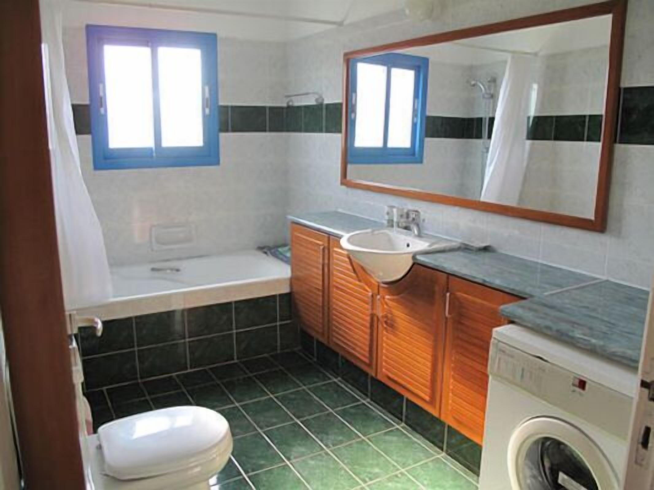 Une salle de bain équipée de toilettes, d’un lavabo, d’un miroir et d’un lave-linge.
