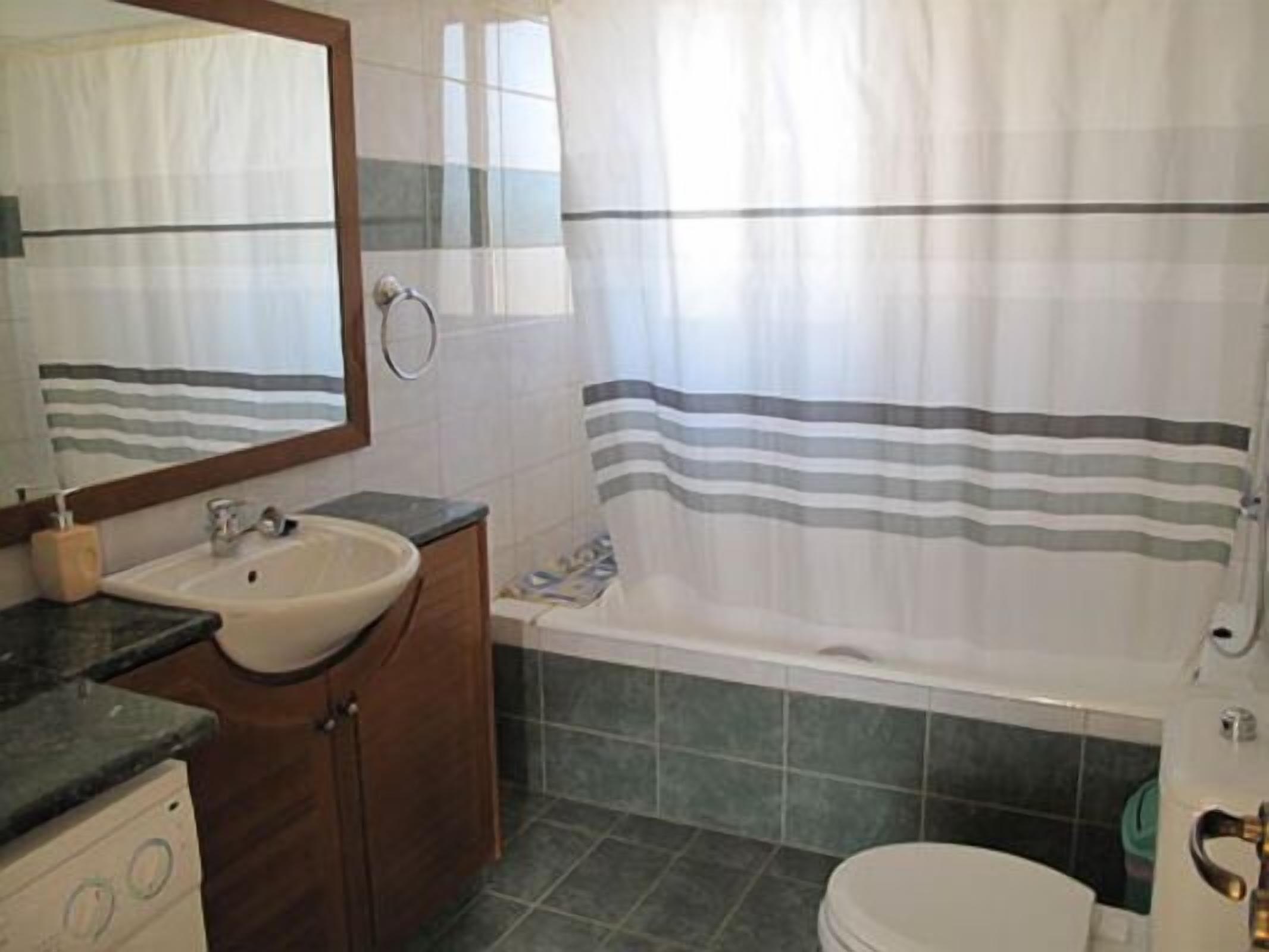 A bathroom with a sink, mirror, vanity, bathtub, and toilet.