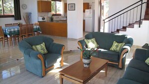 A living room with a sofa set, a coffee table, and a dining area with a table and chairs.
