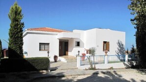 A white building with a tiled roof, a small entrance, and a paved driveway.