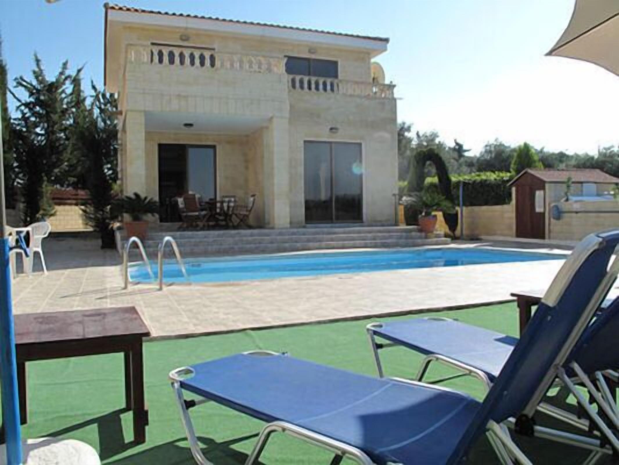 Uma área de piscina com cadeirões de descanso e um edifício com varanda.