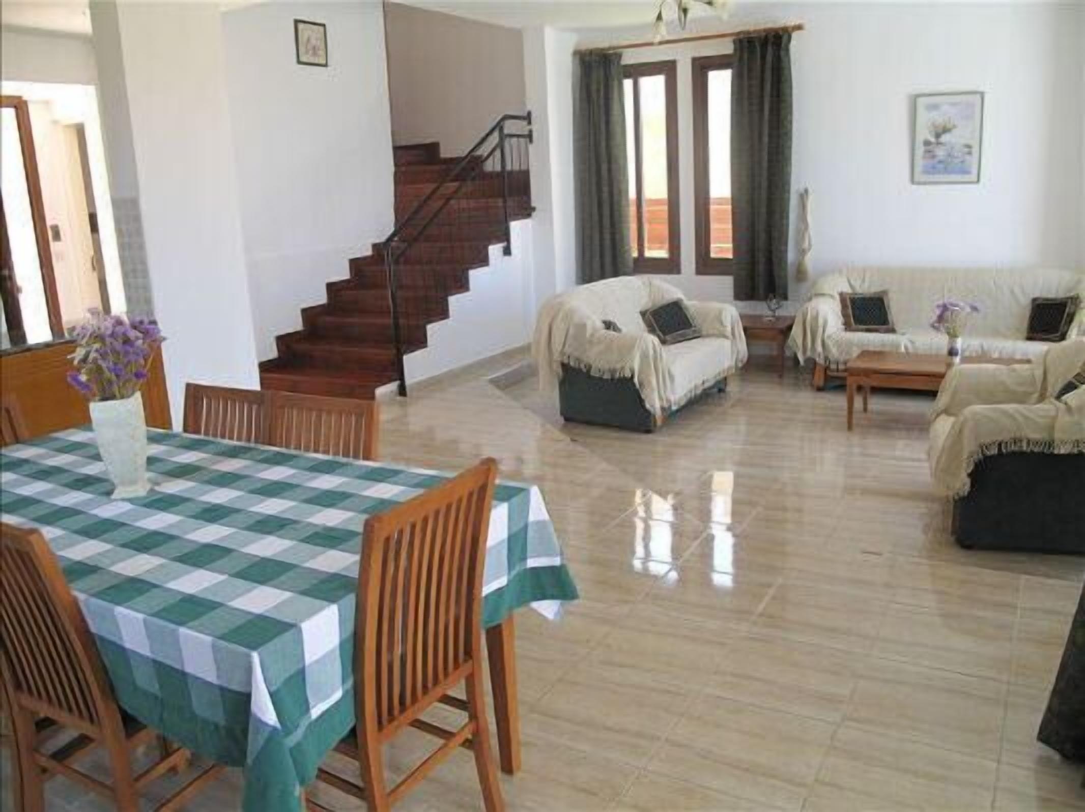 A spacious living area with a dining table, chairs, a sofa, and a staircase.