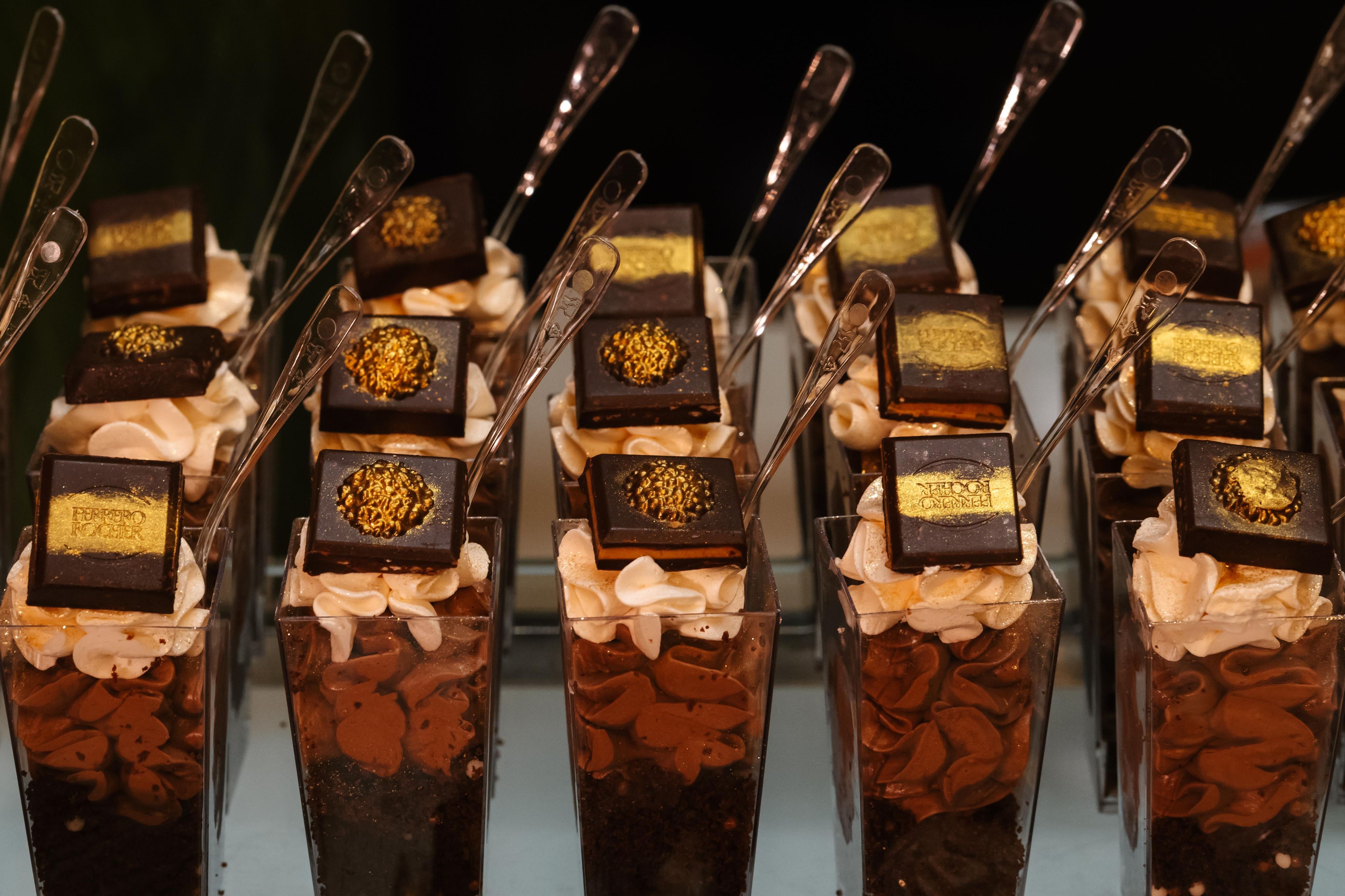 A display of desserts with chocolate pieces and gold leaf decorations.