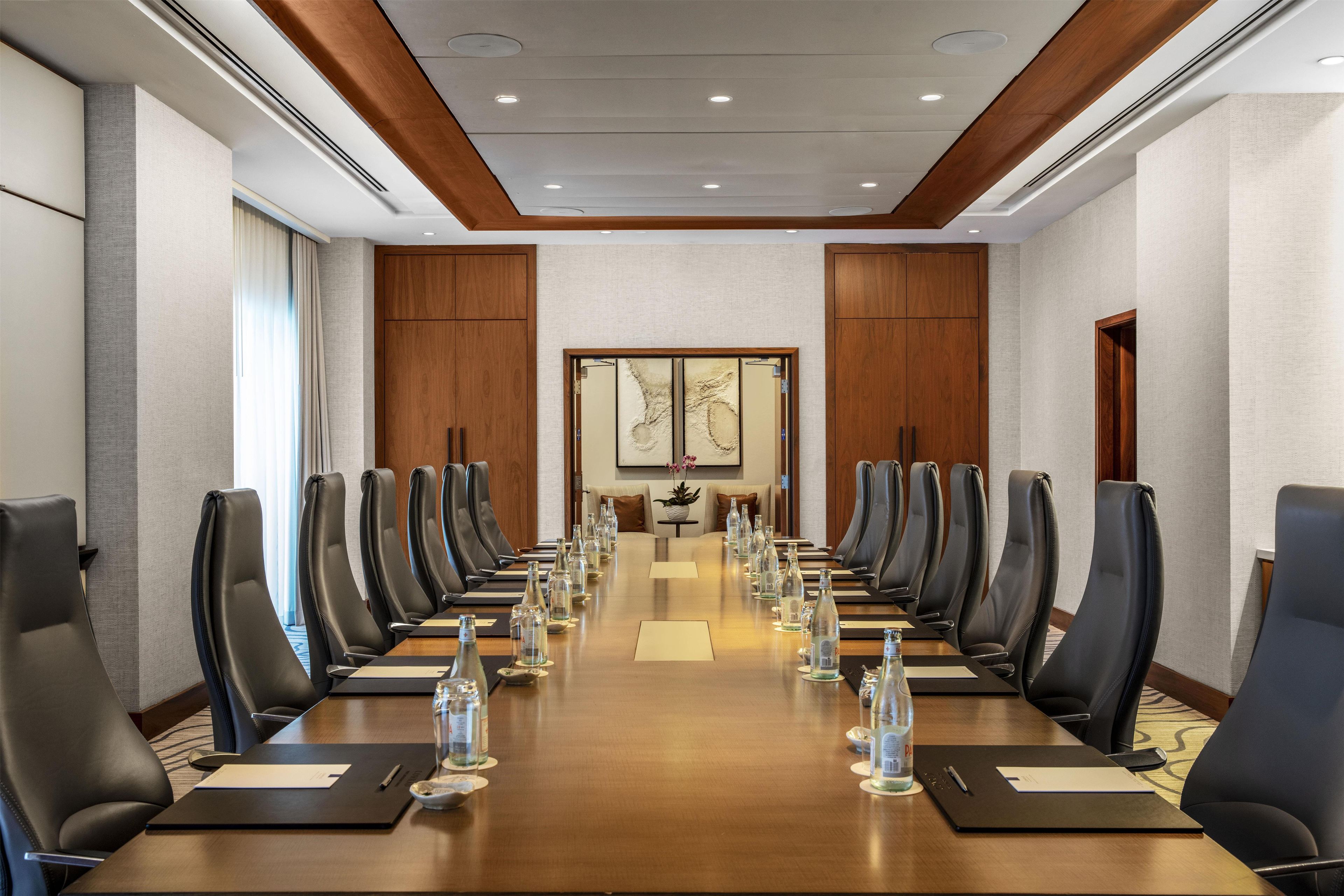A conference room with a long table, multiple chairs, and water bottles.