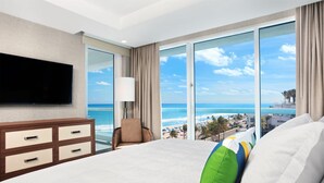 A hotel room with a large bed, a flat-screen TV, a chair, and a balcony with a view of the beach and ocean. - Conrad Fort Lauderdale Beach (Fort Lauderdale)