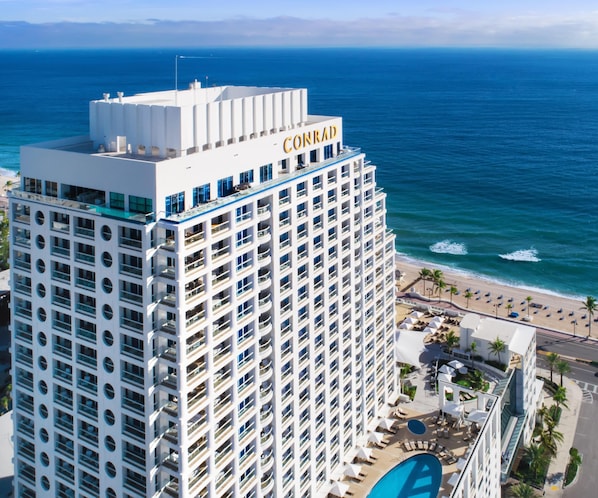 Ein Hochhotel mit Dachterrasse, Pool und Blick auf den Strand.