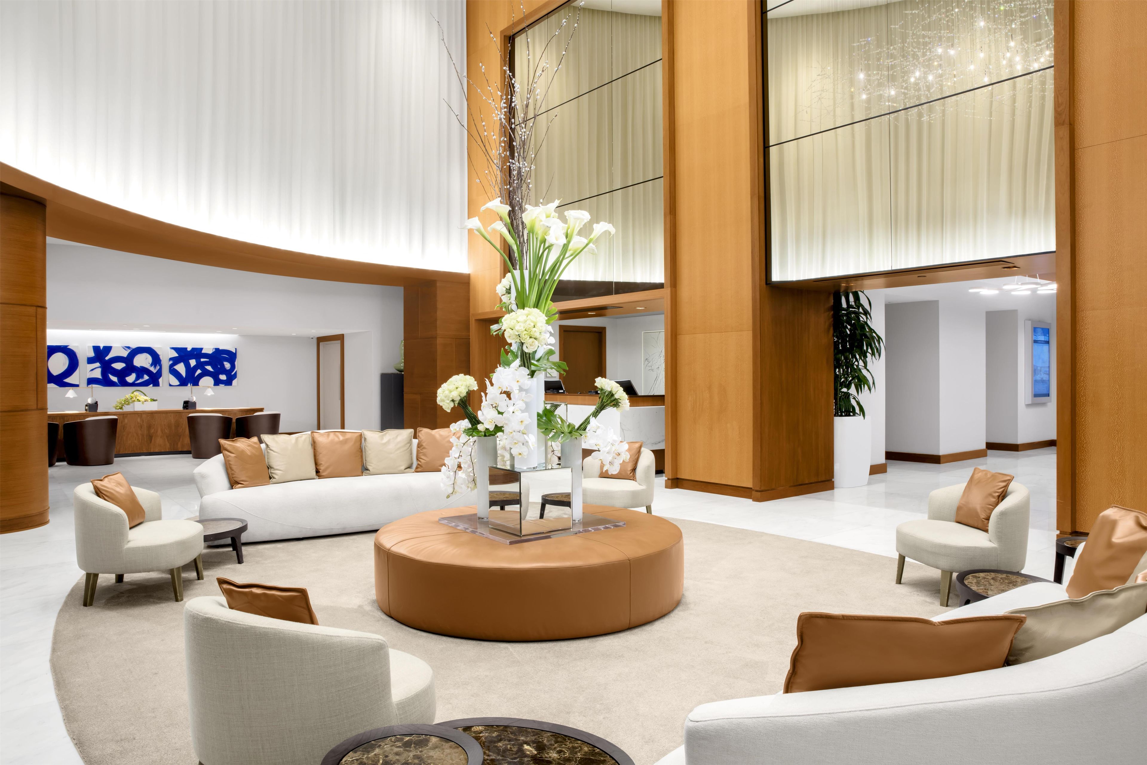 A spacious lobby with a central seating area, a reception desk, and a large window.