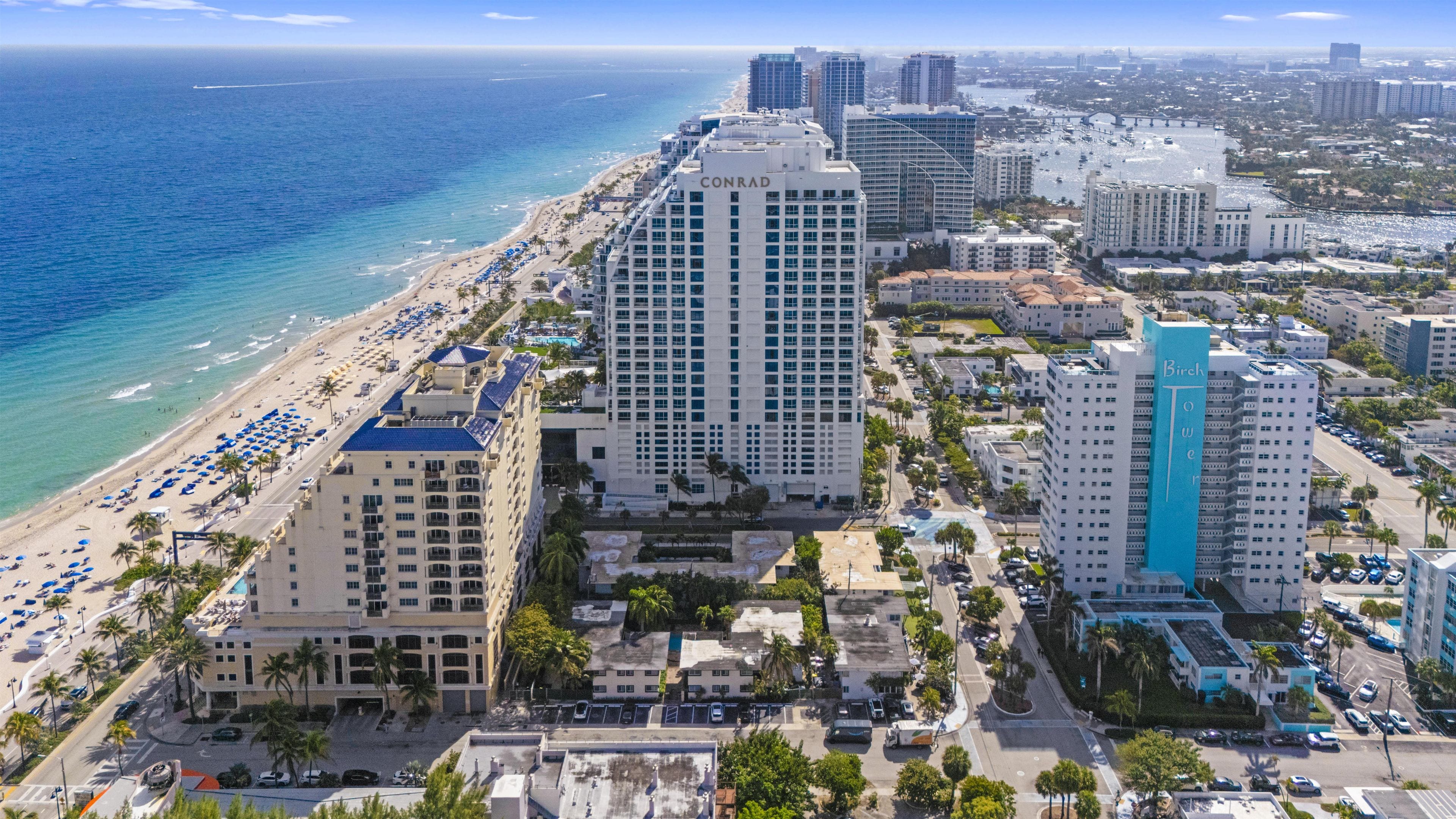 A coastal cityscape with high-rise hotels, a beach, and a marina.
