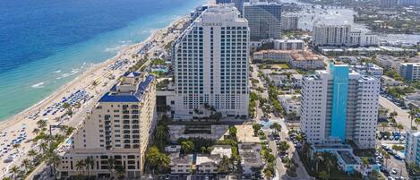 A coastal cityscape with high-rise hotels, a beach, and a marina.