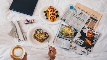 Una cama, un libro, un plato de gofres, un plato de pimientos rellenos, una revista, una taza de café y un par de gafas.