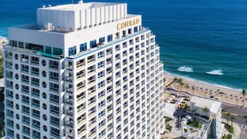 Un hotel moderno con terraza en la azotea, piscina y vistas a la playa.