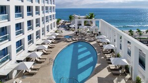 A rooftop pool with lounge chairs and umbrellas, overlooking a beach and ocean. - Conrad Fort Lauderdale Beach (Fort Lauderdale)