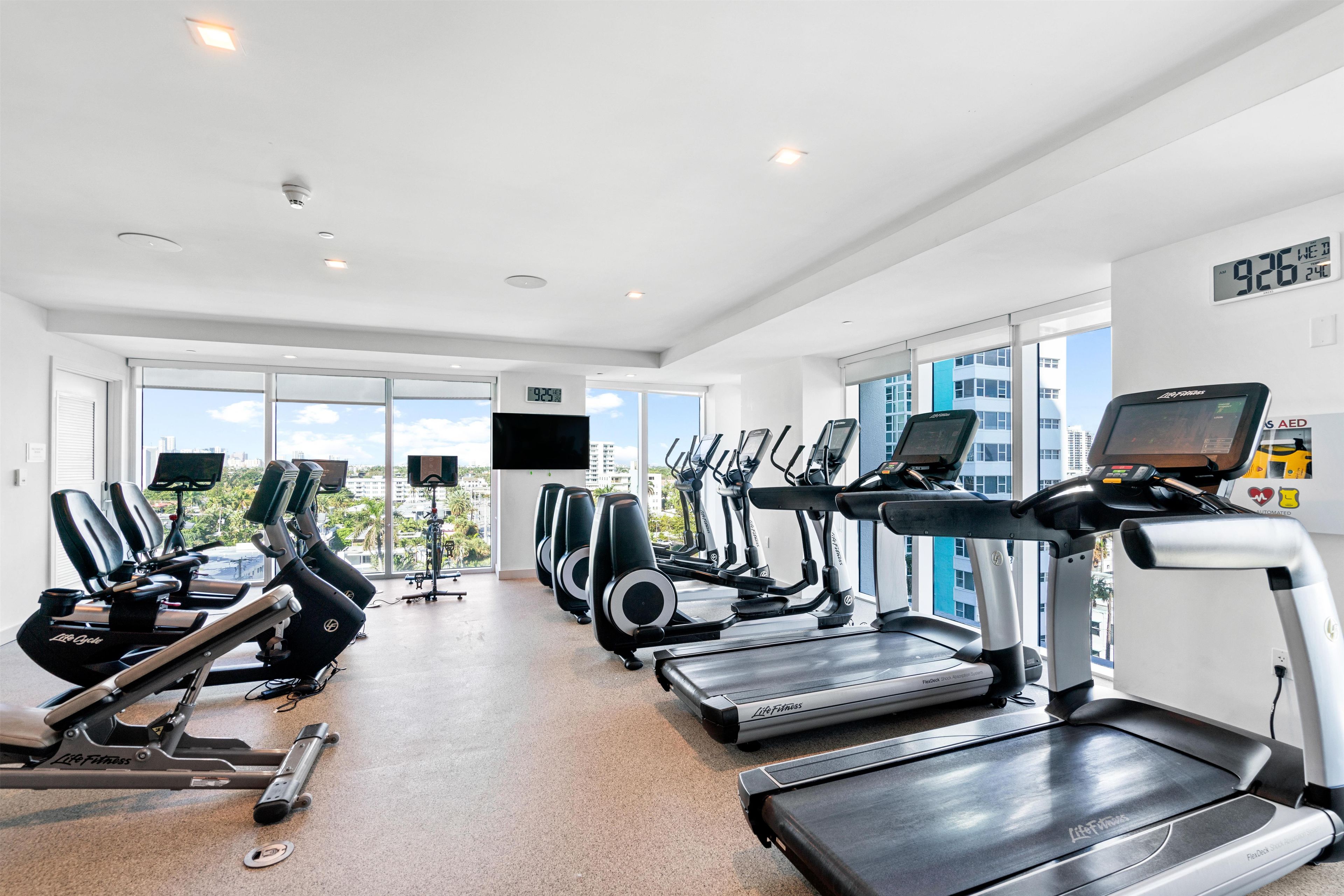 Une salle de sport équipée de tapis de course, de vélos elliptiques et d’un vélo d’appartement.