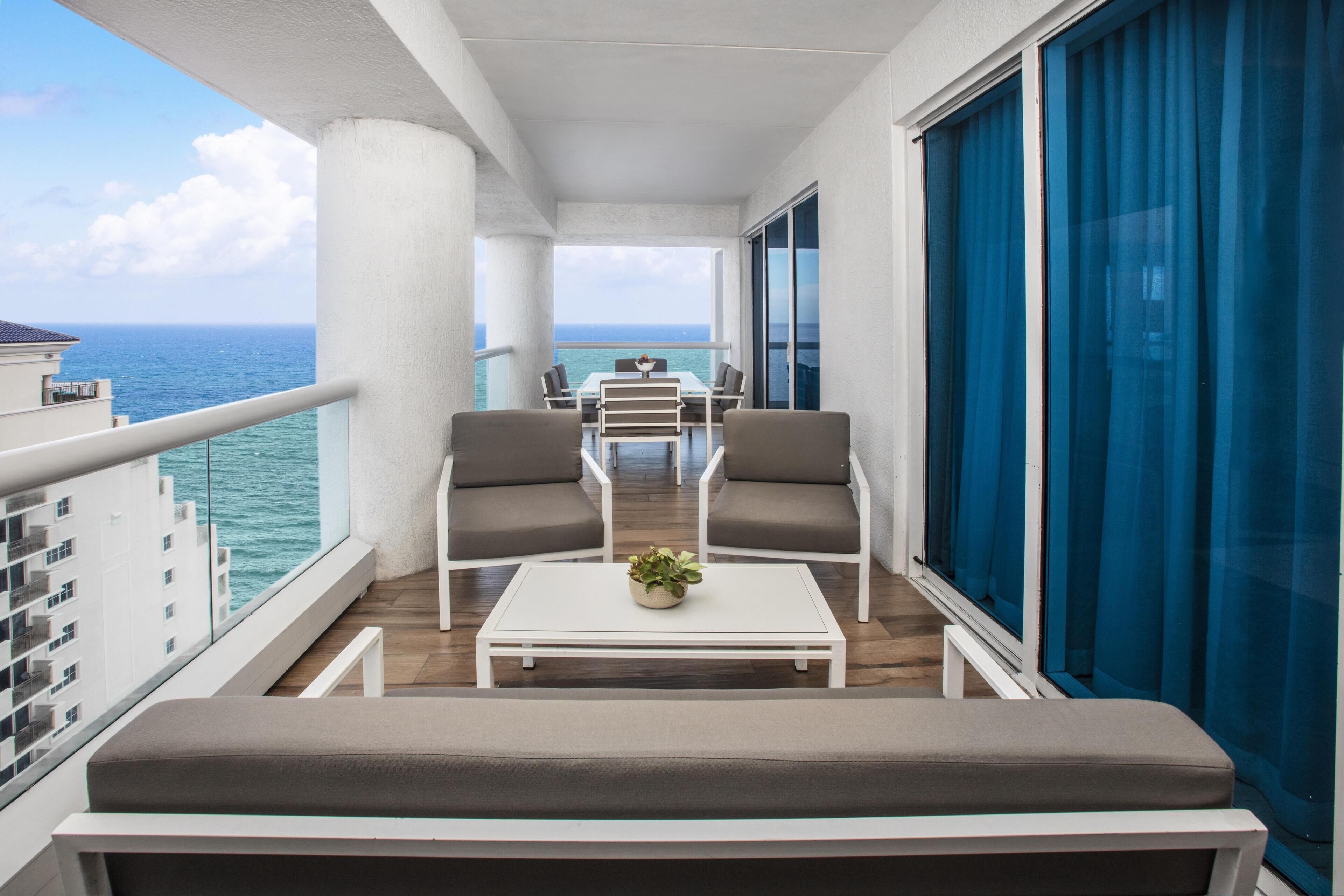 Un balcon avec une table, des chaises et un pot de fleurs.