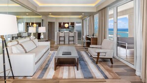 A modern living room with a sofa, armchair, coffee table, and a view of the ocean through large windows. - Conrad Fort Lauderdale Beach (Fort Lauderdale)