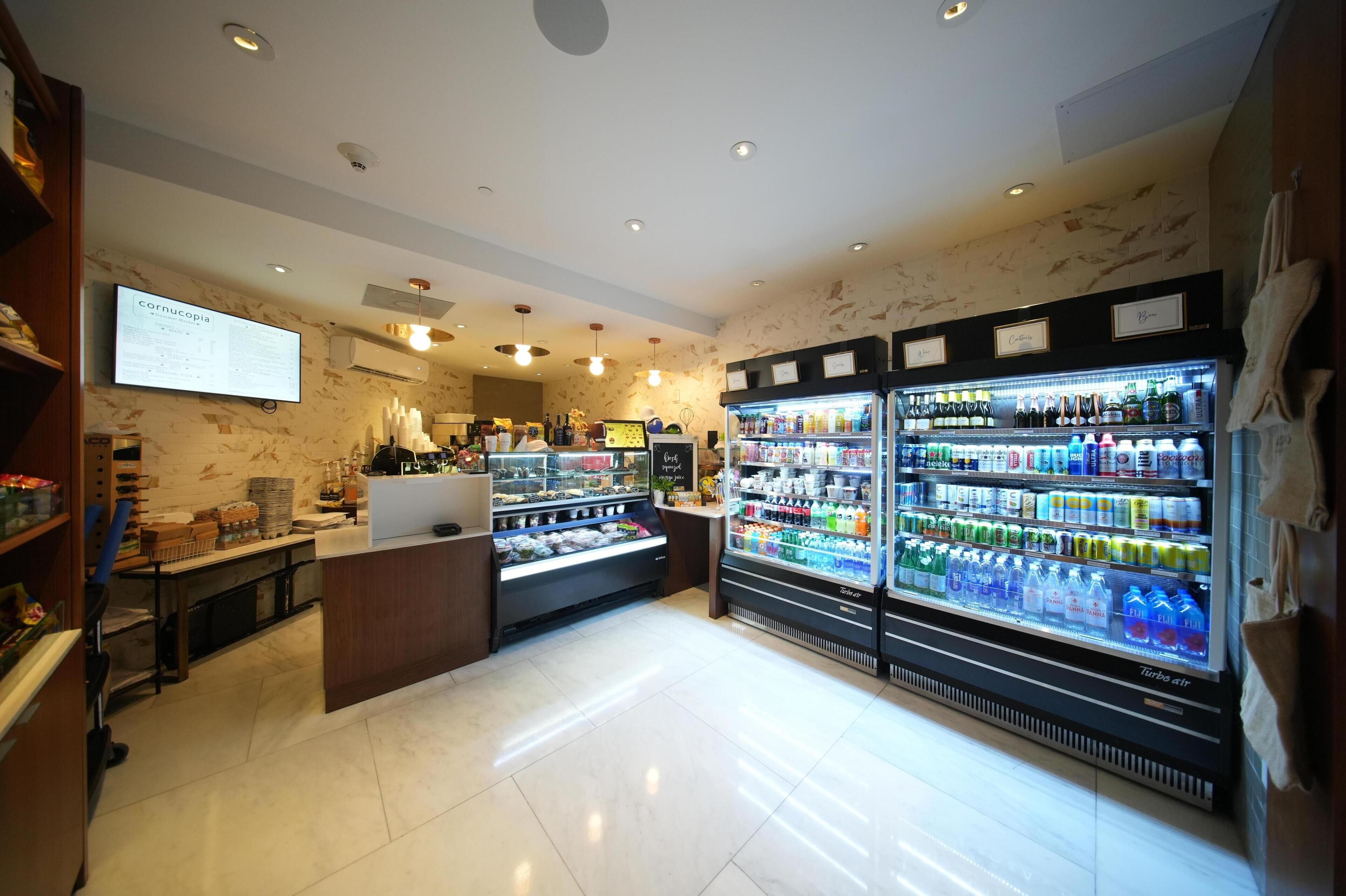 A well-lit store with refrigerated beverage displays and a digital menu board.