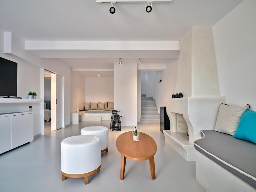 A modern living room with a sofa, ottomans, a coffee table, and a TV.