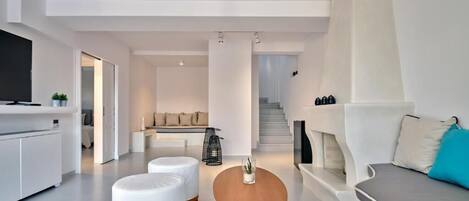 A modern living room with a sofa, ottomans, a coffee table, and a TV.