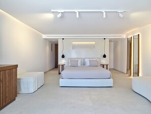 Un dormitorio moderno con una cama grande, mesitas de noche, un banco de madera y una lámpara de techo.