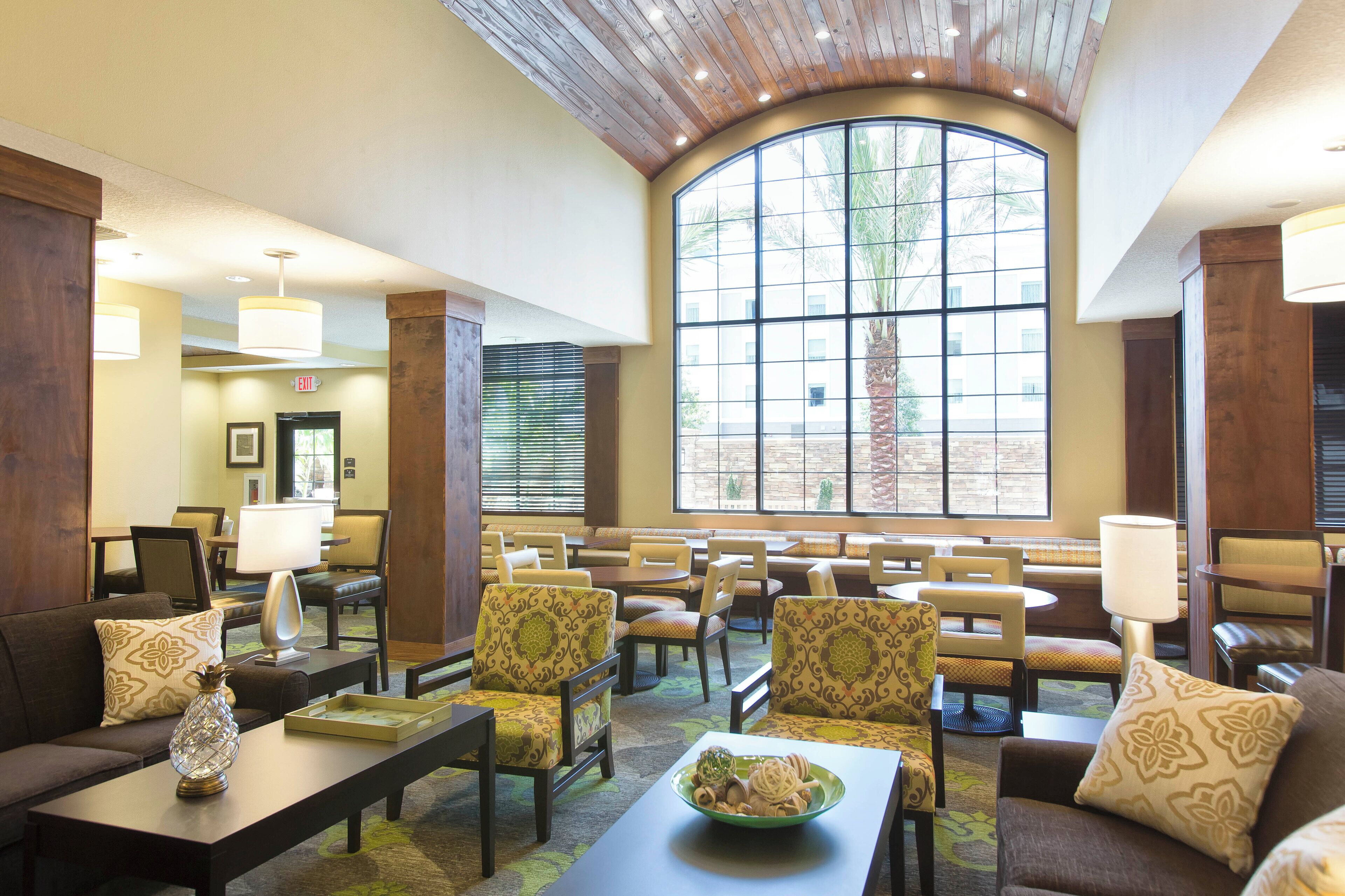 A hotel lobby with a curved ceiling, large windows, seating areas, and a reception desk.