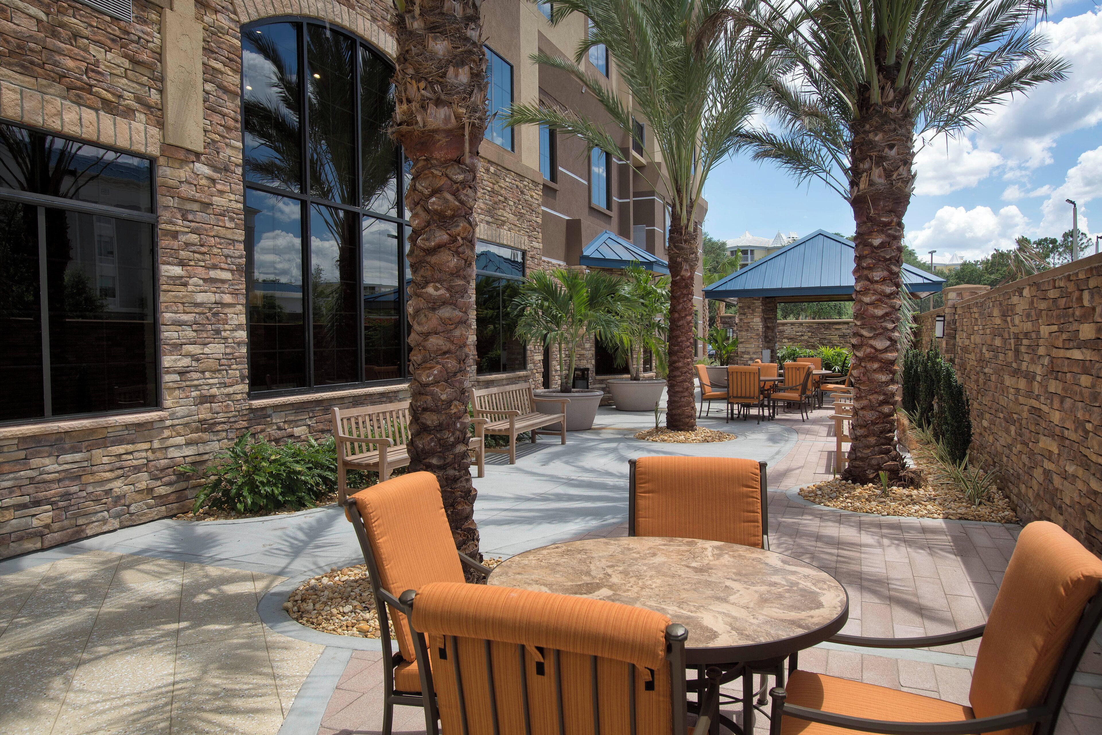 An outdoor patio area with stone walls, palm trees, and outdoor furniture.