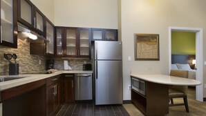 A modern kitchen with dark wooden cabinets, a stainless steel refrigerator, and a small island with a microwave.