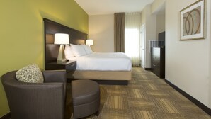 A hotel room with a bed, two bedside lamps, a chair, a desk, and a television.