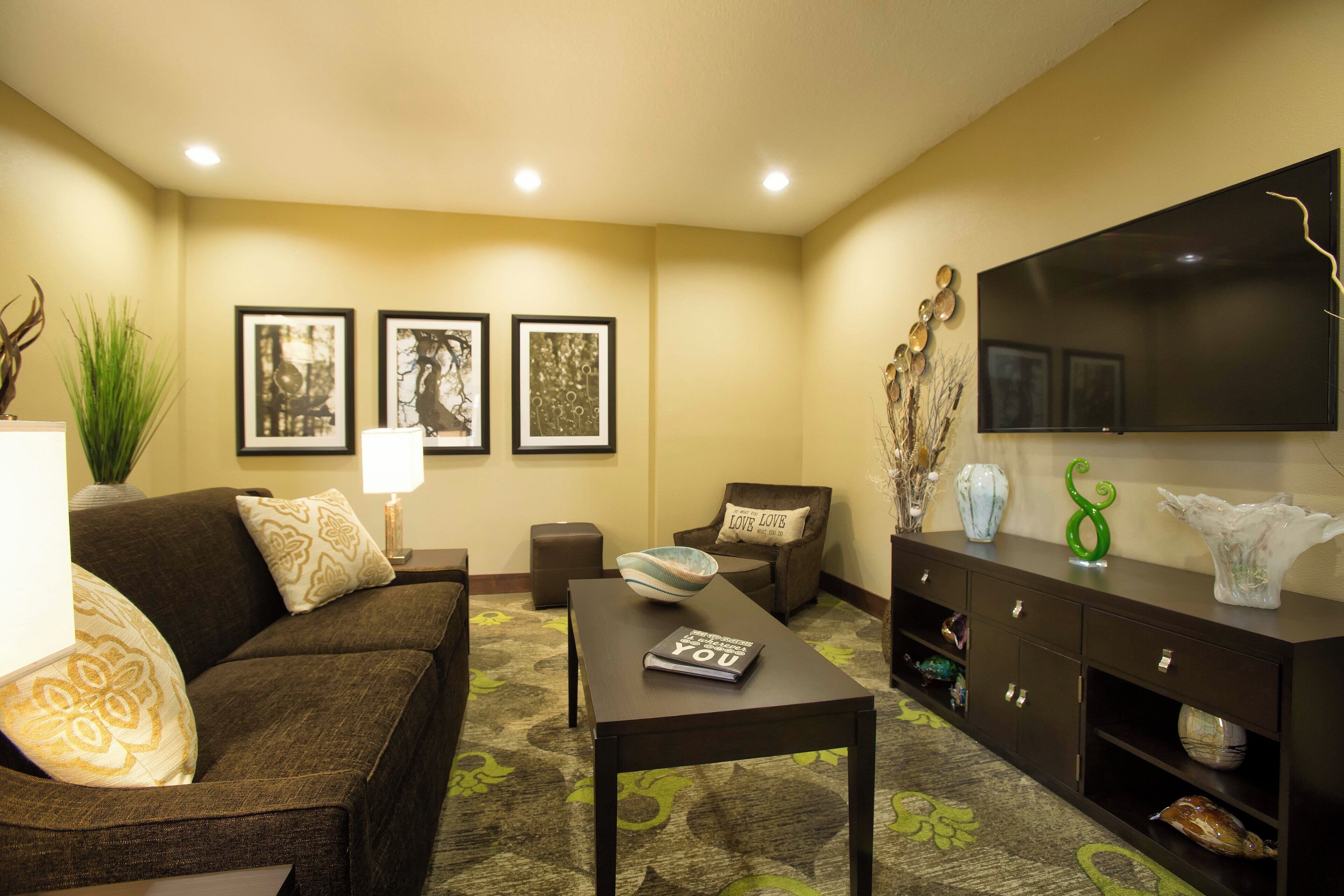 A living room with a sofa, coffee table, and a flat-screen TV on a wall.