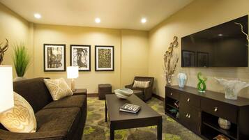 A living room with a sofa, coffee table, and a flat-screen TV on a wall.