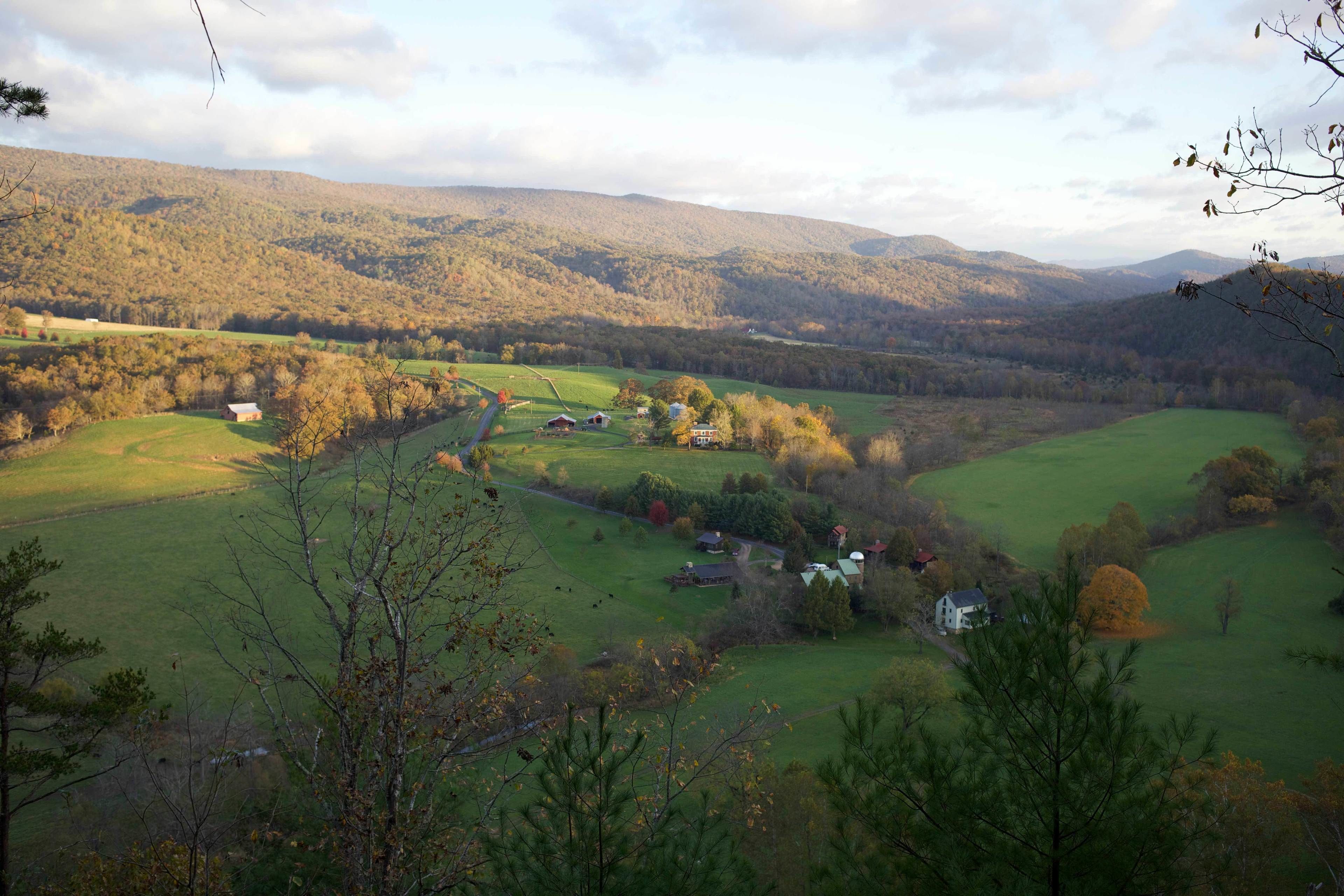 Ländliche Landschaft mit sanften Hügeln, einem kleinen Haus und einer Scheune.